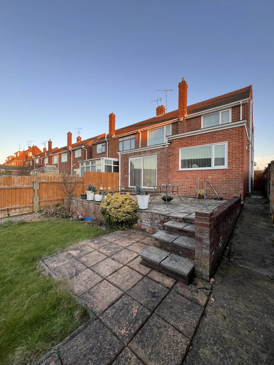 Old, failing patio on a raised brick wall, with very narrow, very tall steps down to the garden.
