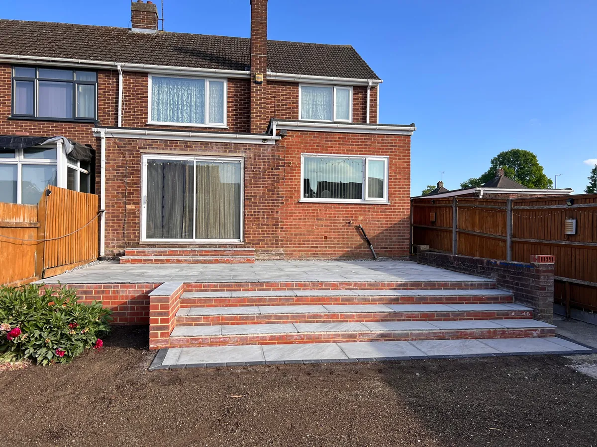 Finished grey patio with wide brick steps and new retaining brickwork in a Luton garden