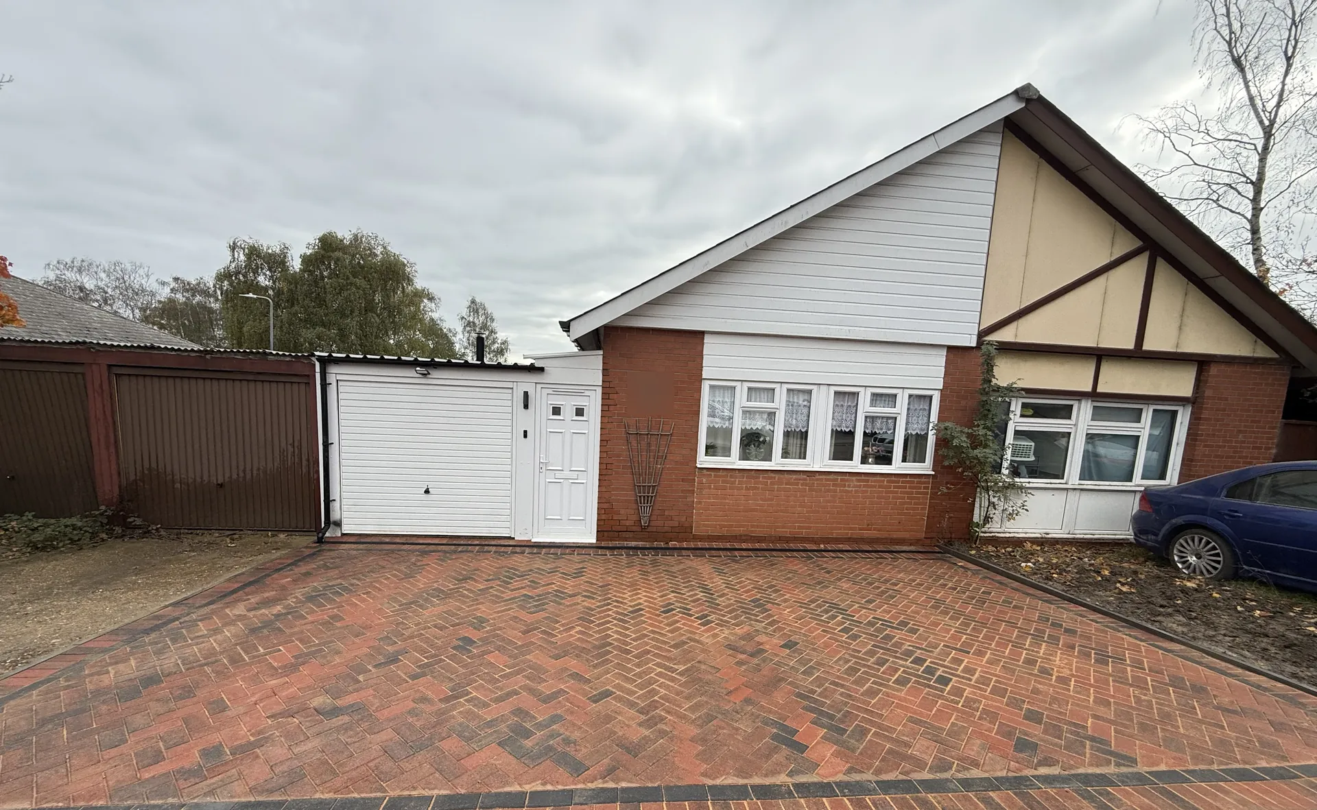 The finished driveway from the road, red herringbone block paving with a charcoal border running up to the garage and the front of the bungalow.