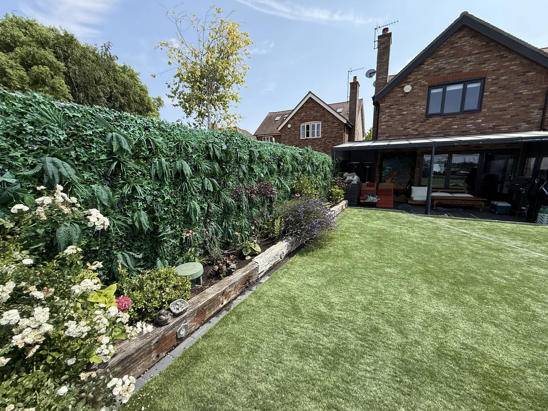 The finished garden in July, with the relaid lawn beside a border in full flower and the house behind.