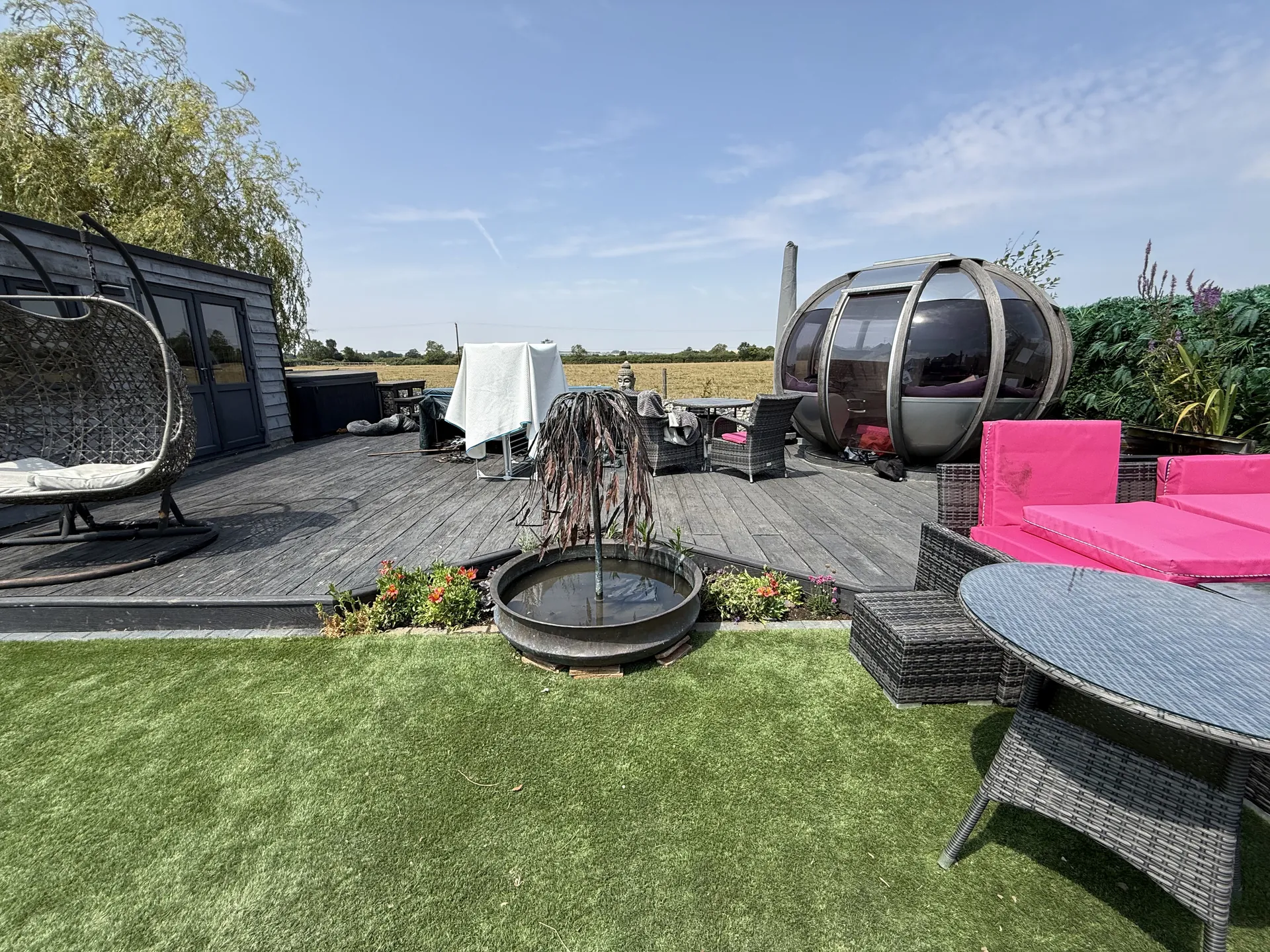 The terrace end of the garden, with the relaid lawn running up to the decking, the seating pod and the table.
