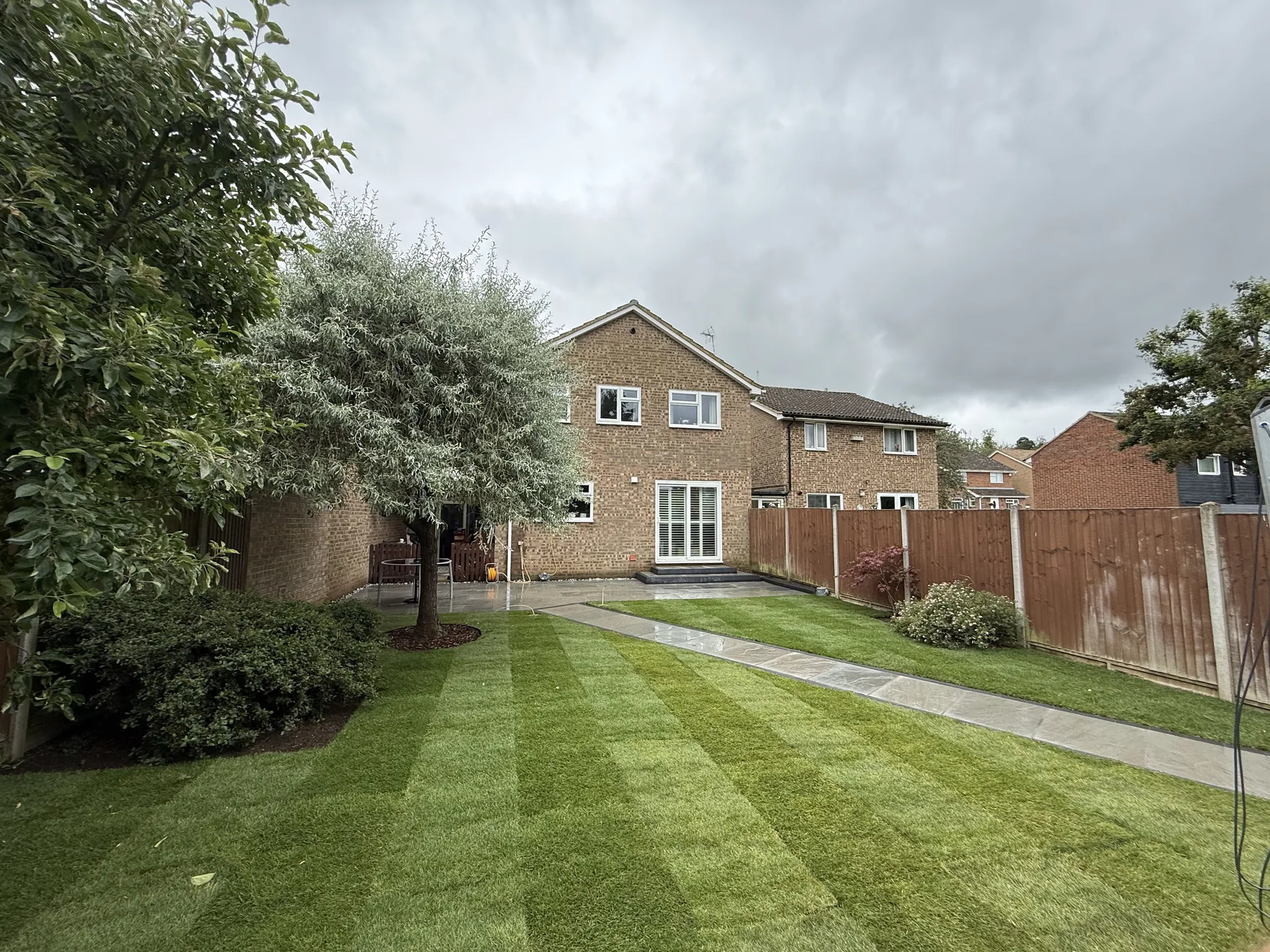 The finished garden from the bottom, with new striped lawn, the sandstone path along one side and the house beyond.