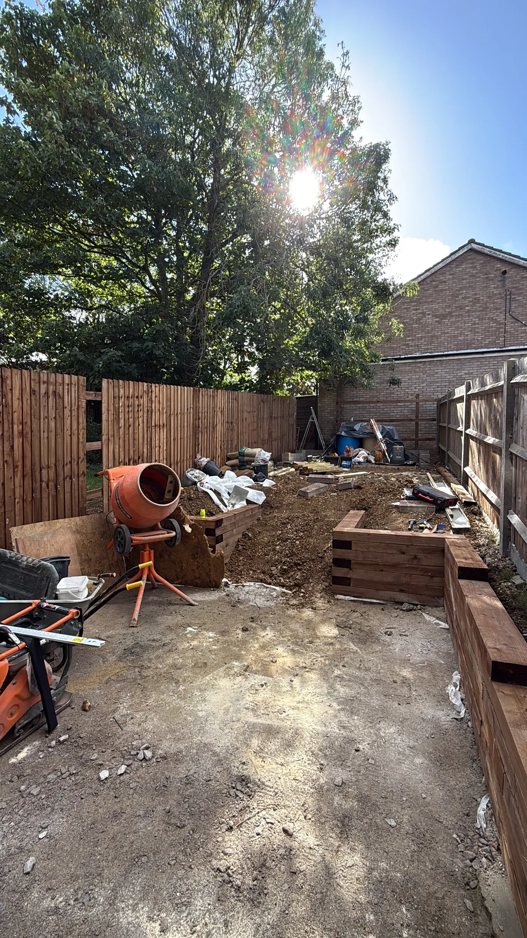 The garden during groundworks, with the mixer, materials and new sleeper walls going in.
