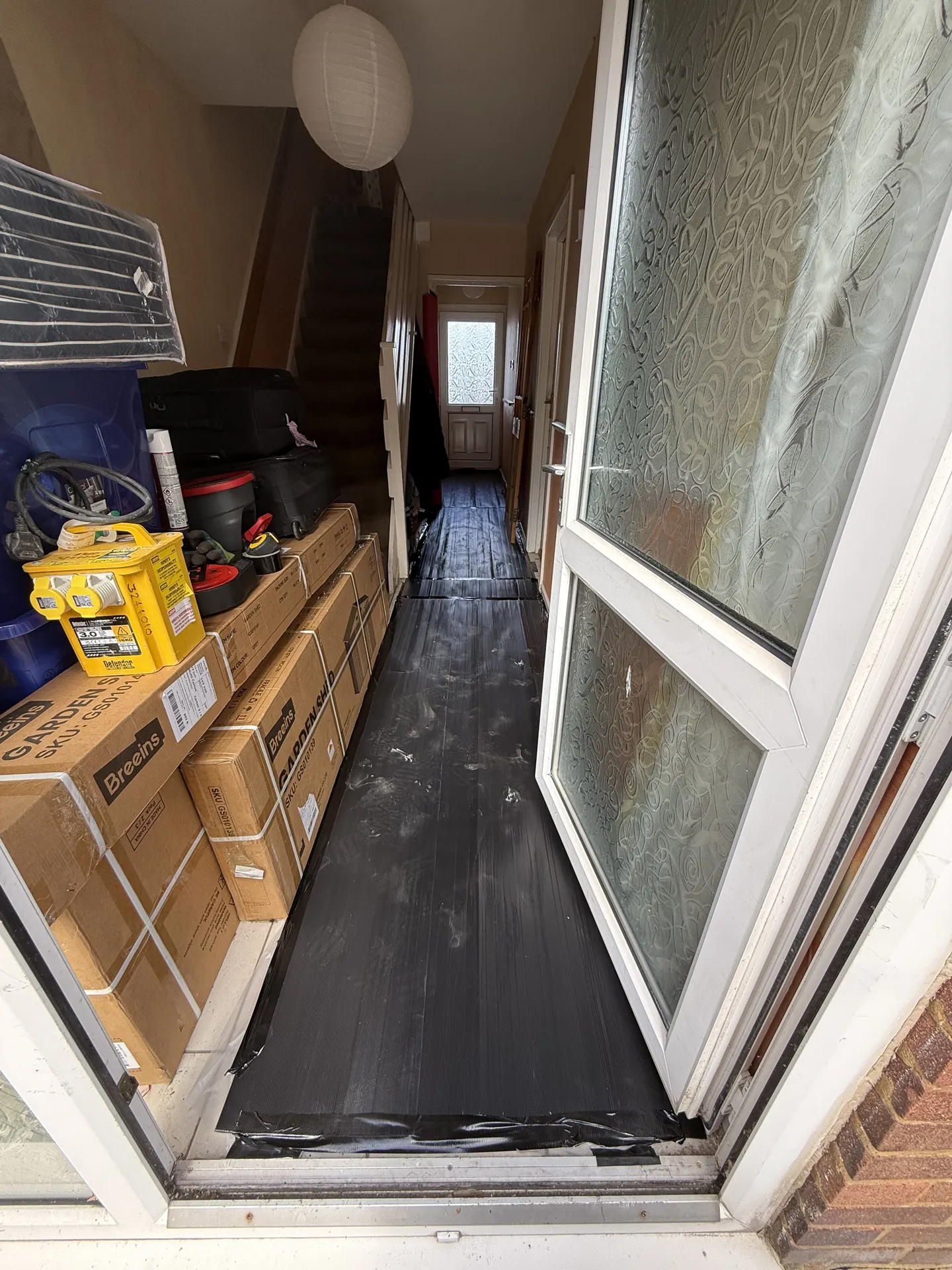 The hallway with protective sheeting laid along the floor from the front door to the back.