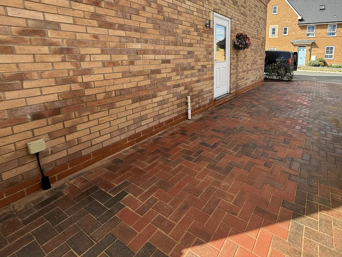 New brindle block paving laid in herringbone up to the side of a house in Milton Keynes, joining the existing drive.