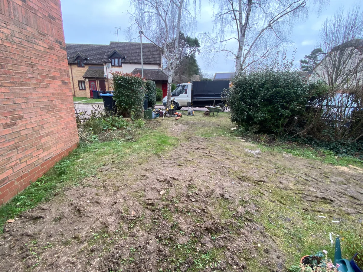 The Welwyn front garden before: a steep, muddy slope running down towards the house, with worn paths and no boundary.